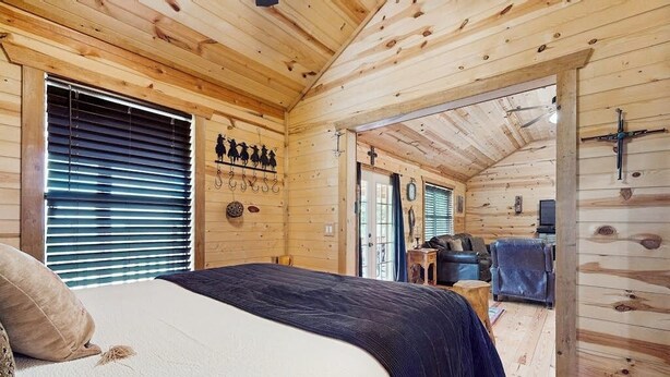 Ein Holzblock-Innenraum mit Bett, einer kleinen Sitzecke und einer Tür, die nach draußen führt.