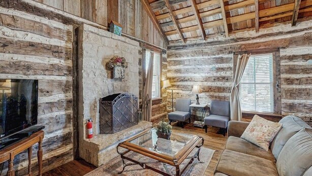 A log cabin interior with a fireplace, a television, and a cozy seating area. - Dog-friendly Suite With a Fireplace - 290 Wine Tasting Trail (Fredericksburg)