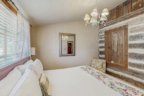 A bedroom with a bed, a chandelier, a mirror, and a wooden wall. - Dog-friendly Suite With a Fireplace - 290 Wine Tasting Trail (Fredericksburg)