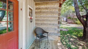 A log cabin with a red door, a wicker chair outside, and a wooden porch. - Dog-friendly Suite With a Fireplace - 290 Wine Tasting Trail (Fredericksburg)
