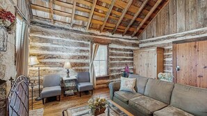 A rustic log cabin interior with a wooden ceiling, a sofa, two armchairs, a small table, and a decorative plant. - Dog-friendly Suite With a Fireplace - 290 Wine Tasting Trail (Fredericksburg)