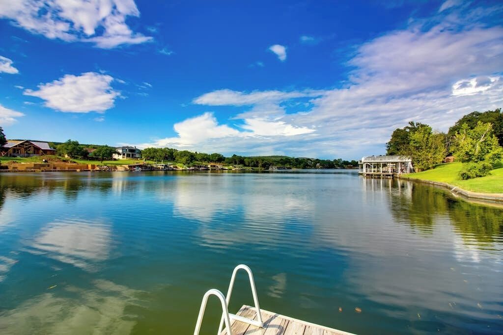 A calm lake with a wooden dock and a gazebo on the right.