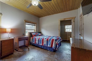 A bedroom with a bed, a desk, a ceiling fan, and a window. - Renovated Waterfront Home With Wifi, Lake Views, Dock & Boat Lift - Dogs OK (Burnet)