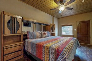 A bedroom with a wooden headboard, a bed with a patterned bedspread, a ceiling fan, and a window. - Renovated Waterfront Home With Wifi, Lake Views, Dock & Boat Lift - Dogs OK (Burnet)