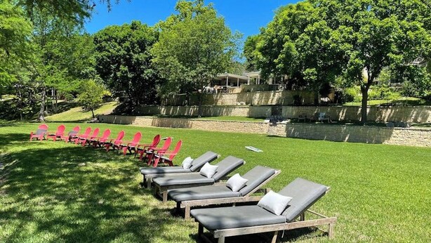 A row of sun loungers on a grassy lawn with a stone wall and trees in the background. - Inviting Waterfront Home With Pool, Patio, Fireplace, W/d, & Dog-friendly (Hunt)