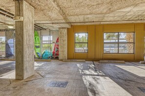 A parking garage with concrete pillars, yellow walls, and large windows. - Dog-friendly & Spacious Condo With Lake Views, Large Balcony, & Pool (Horseshoe Bay)