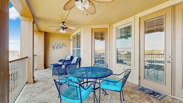A covered patio with a round table and chairs, ceiling fans, and a view through the glass doors.