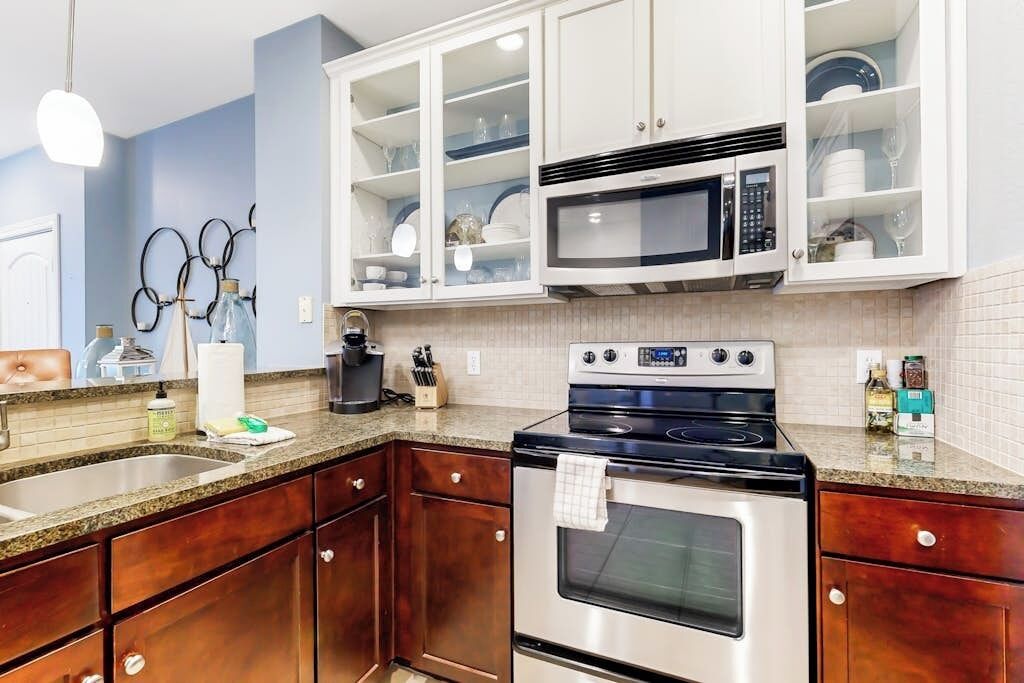 A kitchen with wooden cabinets, a stainless steel stove, a microwave, and a sink.