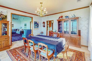 A dining room with a table set for four, a chandelier, and a large cabinet with glass doors. - 2-story Home With Covered Patio, Balcony, Fireplace, Streaming, Great Views, W/D (Kerrville)