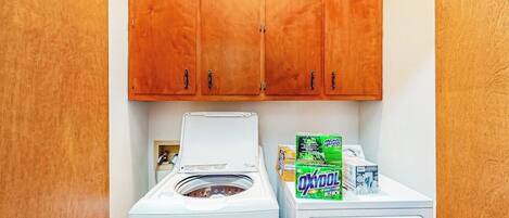 A laundry area with a washing machine, dryer, and detergent boxes.