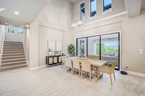 A spacious room with a dining area, a staircase, and a large sliding glass door leading to an outdoor patio. - Exquisite Dog-friendly Home With Balcony, Enclosed Yard, Central AC, & W/D (Leander)