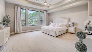 A bedroom with a bed, a nightstand, a dresser, a ceiling fan, and large windows. - Exquisite Dog-friendly Home With Balcony, Enclosed Yard, Central AC, & W/D (Leander)