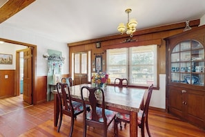 A dining area with a wooden table and chairs, a chandelier, and a cabinet with glass doors. - Charming, Dog-friendly Home With Patio, Grill, & Parking - Close to Town (Fredericksburg)
