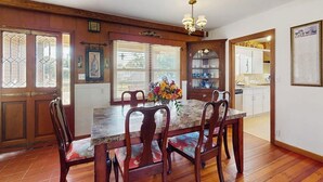 A dining area with a wooden table and chairs, a chandelier, and a window with blinds. - Charming, Dog-friendly Home With Patio, Grill, & Parking - Close to Town (Fredericksburg)