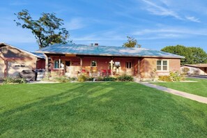 A single-story brick house with a covered porch, a front yard, and a garage. - Charming, Dog-friendly Home With Patio, Grill, & Parking - Close to Town (Fredericksburg)