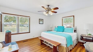 A bedroom with a bed, a ceiling fan, a window with blinds, a bedside table, and a bench. - Charming, Dog-friendly Home With Patio, Grill, & Parking - Close to Town (Fredericksburg)