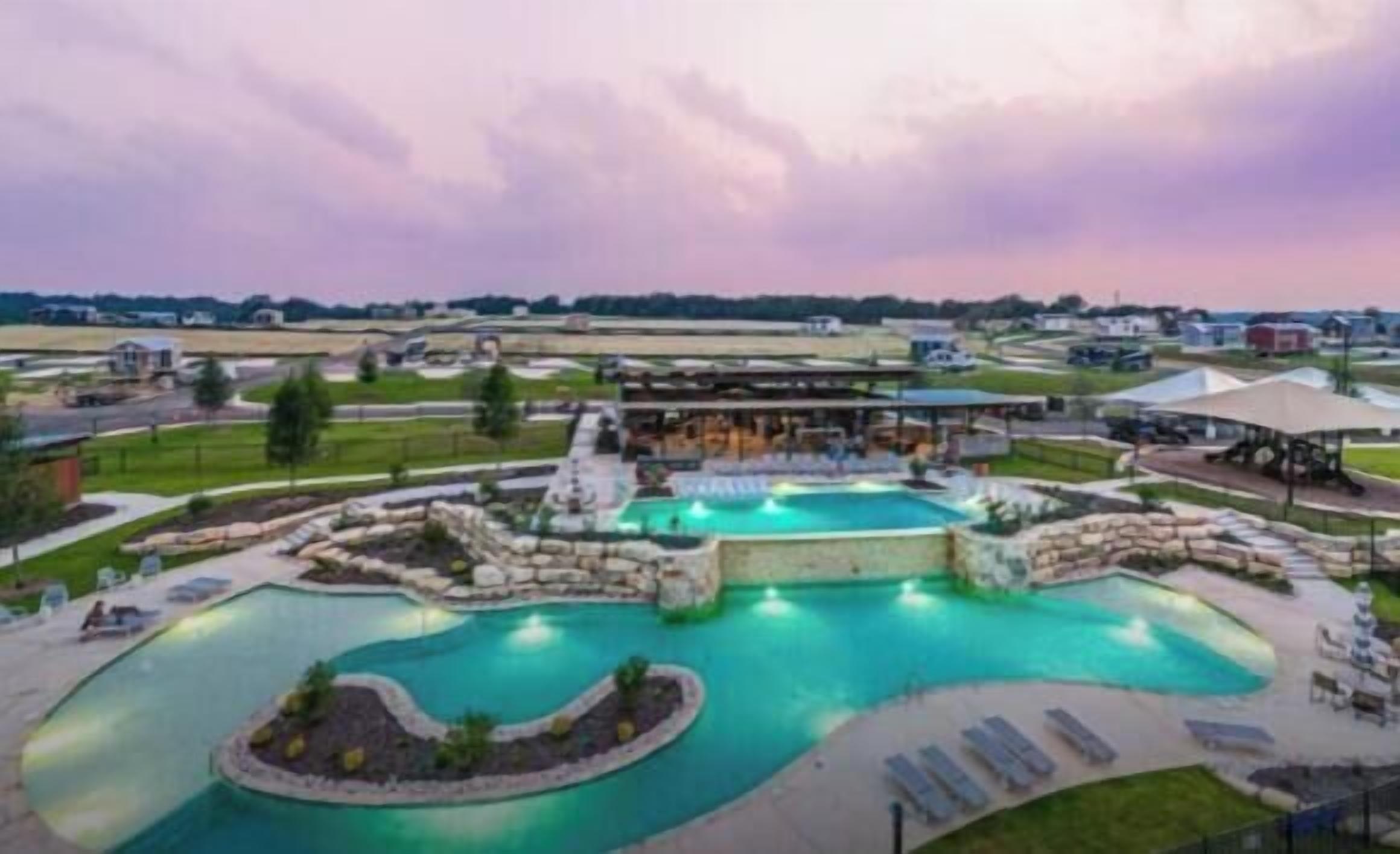 A resort with a large swimming pool, outdoor seating, and a covered area.