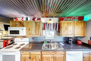 A kitchen with wooden cabinets, a microwave, a stove, a sink, and a blender. - Charming Dog-friendly Lakefront Home With Lake View, Dock, & Washer/dryer (Kingsland)