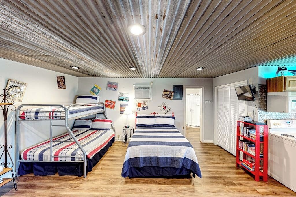 Ein Zimmer mit Etagenbetten, einem roten Bücherregal und einer Küchenzeile.