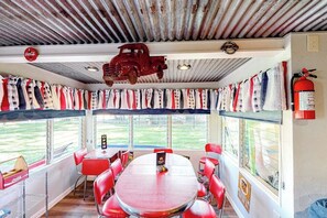 A dining area with a red table and chairs, a vintage car decoration, and a fire extinguisher on the wall. - Charming Dog-friendly Lakefront Home With Lake View, Dock, & Washer/dryer (Kingsland)