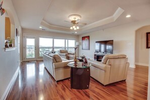 A spacious living room with a large sofa, a coffee table, and a television. - Wonderful Lake-view Home With Game Room & Firepit (Leander)