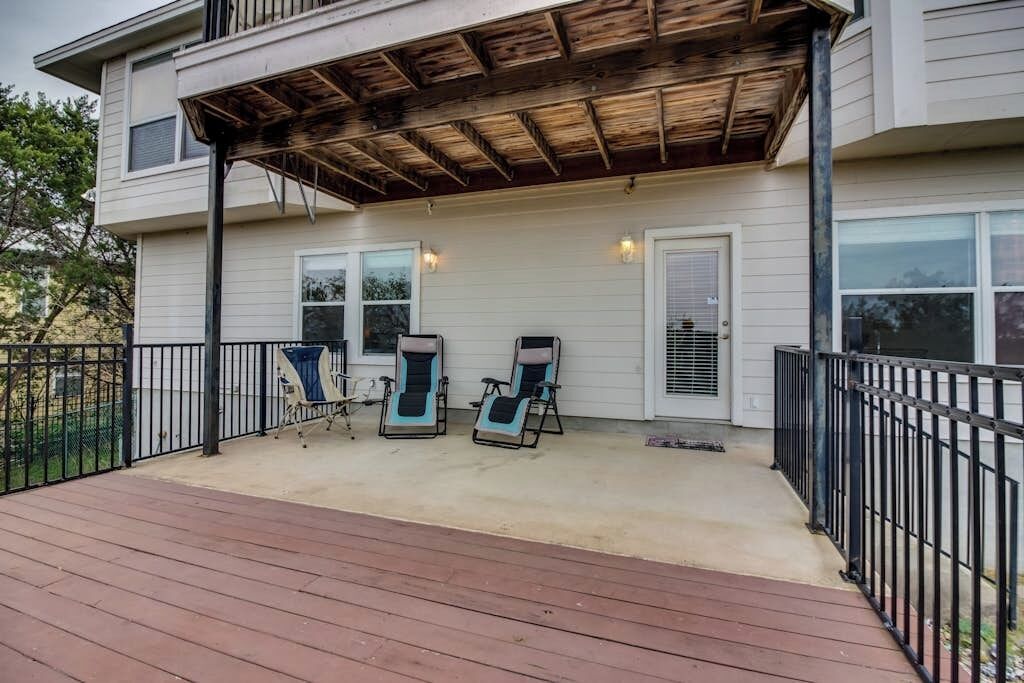 A covered deck with two lounge chairs and a small table.