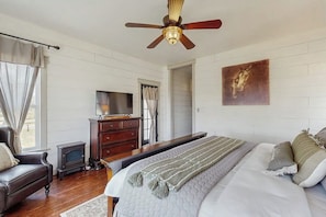 A bedroom with a bed, a wooden dresser, a television, and a ceiling fan. - Cozy Ranch Home With Full Kitchen, Living Room, Hot Tub, Pet-friendly & Fireplace (Fredericksburg)