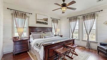 A bedroom with a wooden bed, a ceiling fan, and a view of the outdoors.