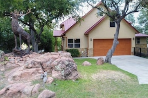 A house with a garage, a deer statue, and a rock garden. - Lakefront Home With Wifi, Entertainment, Dock & Lake Views - Dogs OK (Burnet)