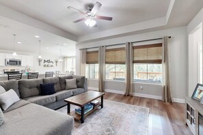 A spacious living room with a gray sectional sofa, a wooden coffee table, and a ceiling fan. - Cozy Lago Vista Home With Private Pool Table, Mile From The Stunning Lake Travis (Leander)