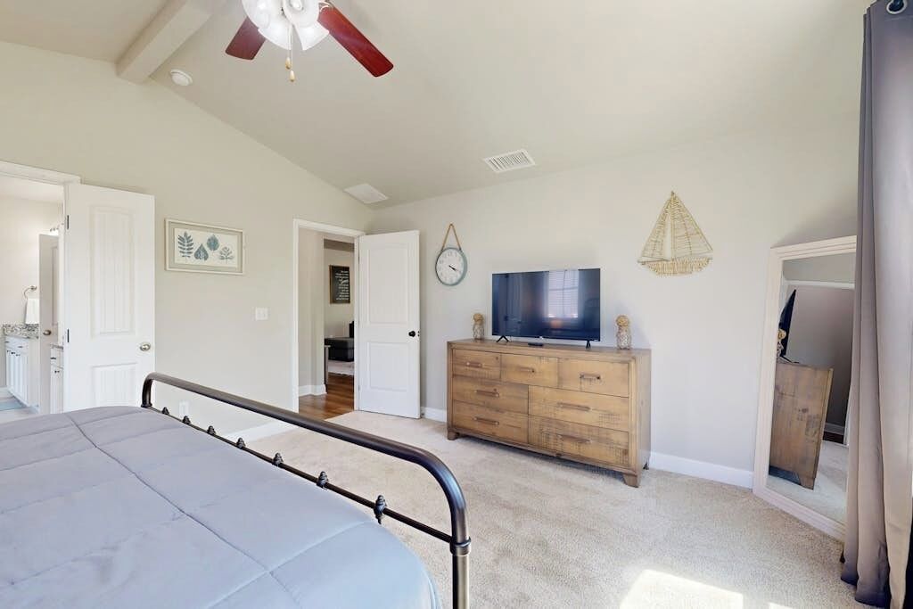 Ein Schlafzimmer mit einem Bett, einer Holzkommode, einem Fernseher und einem Deckenventilator.