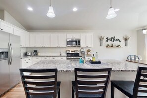 A modern kitchen with white cabinets, a granite countertop, and a central island with seating. - Cozy Lago Vista Home With Private Pool Table, Mile From The Stunning Lake Travis (Leander)