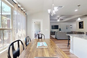 Una cocina moderna con una isla central, una zona de comedor con mesa de madera y vistas a través de amplios ventanales.