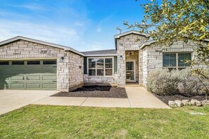 A two-story house with a stone facade, a garage, and a landscaped front yard. - Cozy Lago Vista Home With Private Pool Table, Mile From The Stunning Lake Travis (Leander)