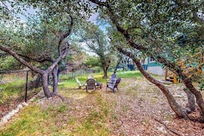 An outdoor seating area with chairs and a table, surrounded by trees and a fence. - Cozy Lago Vista Home With Private Pool Table, Mile From The Stunning Lake Travis (Leander)