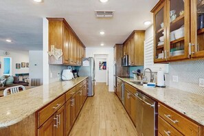 A kitchen with wooden cabinets, a granite countertop, a refrigerator, and a microwave. - Waterfront Home With Kayaks, Game Room, Firepit, & Enormous Deck (Kingsland)