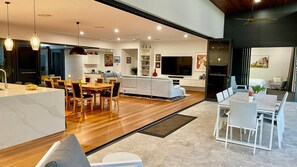Eine moderne Küche mit Essbereich, ein Wohnzimmer mit Sofa und Fernseher, sowie ein separater Esstisch mit Stühlen.