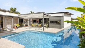 Ein modernes Haus mit Swimmingpool, Sitzgelegenheit im Freien und einer überdachten Terrasse.
