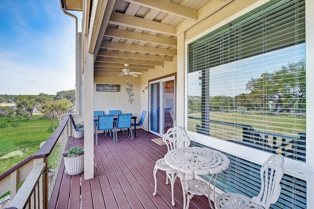 A covered outdoor area with a table and chairs, a ceiling fan, and a view of the surrounding landscape.