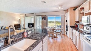 A modern kitchen with granite countertops, a dining area with wooden chairs, and a view of the outdoors. - 2-story Townhouse With Balcony, Outdoor Pool, Tennis, Grill, Basketball, & AC (Leander)