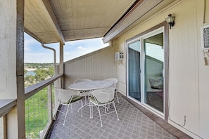 A balcony with a table and chairs, a sliding glass door, and a view of the landscape. - 2-story Townhouse With Balcony, Outdoor Pool, Tennis, Grill, Basketball, & AC (Leander)