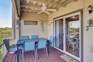 Un patio techado con una mesa y sillas, un ventilador de techo y un letrero de bienvenida.