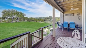 A covered porch with a view of a green lawn and trees, a table with chairs, and a 'Welcome to our porch' sign. - 2-story Townhouse With Balcony, Outdoor Pool, Tennis, Grill, Basketball, & AC (Leander)