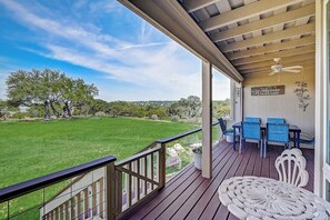 A covered porch with a view of a green lawn and trees, a table with chairs, and a 'Welcome to our porch' sign. - 2-story Townhouse With Balcony, Outdoor Pool, Tennis, Grill, Basketball, & AC (Leander)
