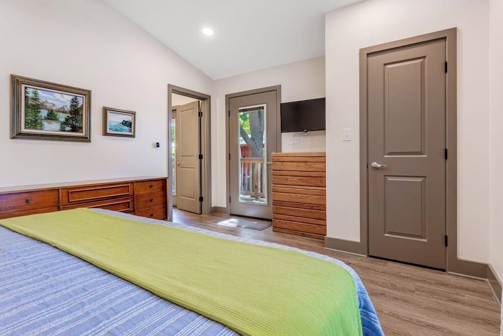 Ein Schlafzimmer mit einem Bett, einer Holzkommode und einem Fernseher an der Wand.