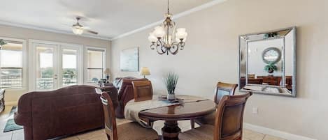 A dining area with a chandelier, a round table, and chairs.