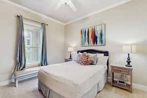 A bedroom with a bed, a bench, a nightstand, a lamp, and a ceiling fan. - Waterfront Condo With Furnished Balcony, Central AC, & Washer/dryer (Horseshoe Bay)
