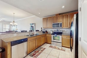 A modern kitchen with wooden cabinets, stainless steel appliances, and a central island. - Waterfront Condo With Furnished Balcony, Central AC, & Washer/dryer (Horseshoe Bay)
