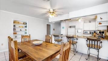A modern kitchen with white cabinets, a wooden dining table, and bar stools.