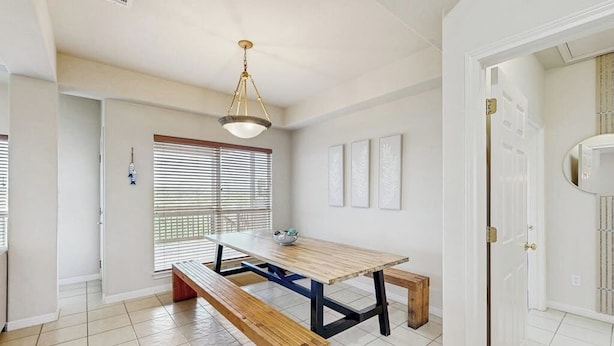 Un comedor con una mesa y bancos de madera, una lámpara colgante y una puerta que da a otra habitación.